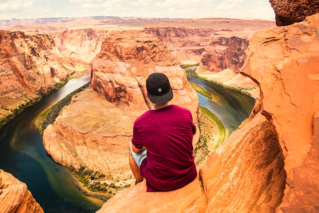 man sitting at horseshoe bend in the grand canyon