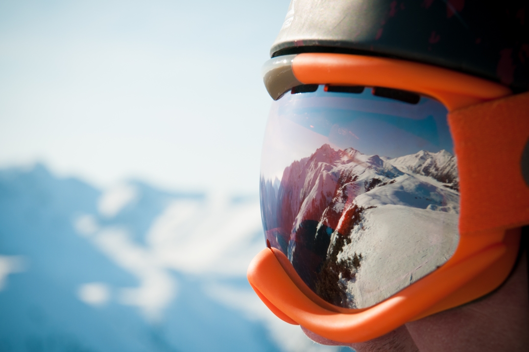 mans ski goggles reflecting mountain view